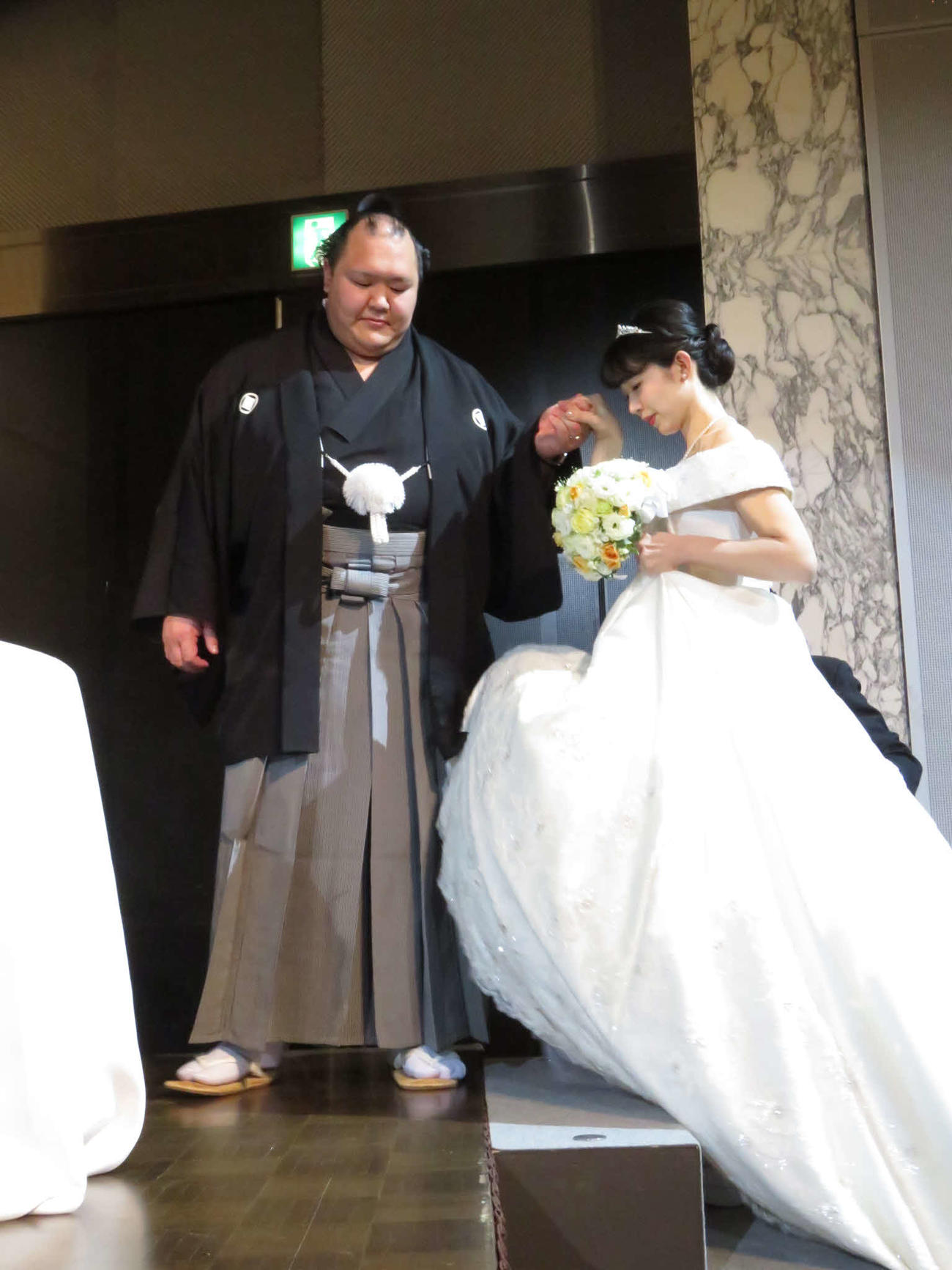 結婚披露宴でウエディングケーキ入刀前に真美夫人をエスコートする北勝富士