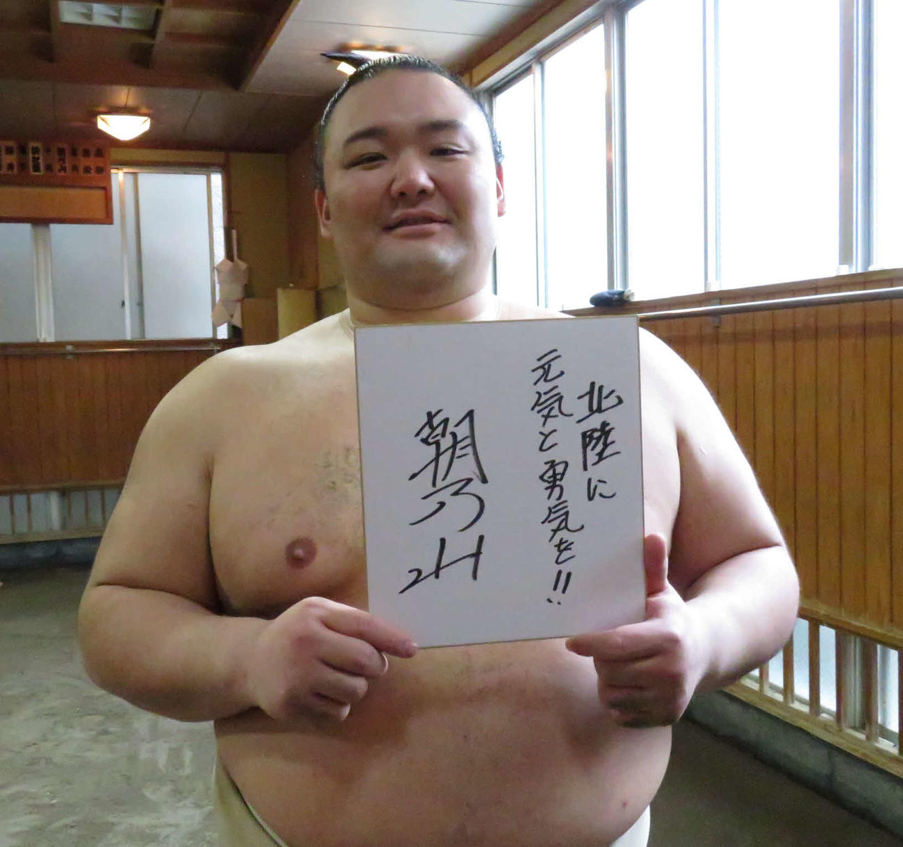 「北陸に元気と勇気を!!」と記した色紙を手に笑顔を見せる朝乃山（撮影・高田文太）