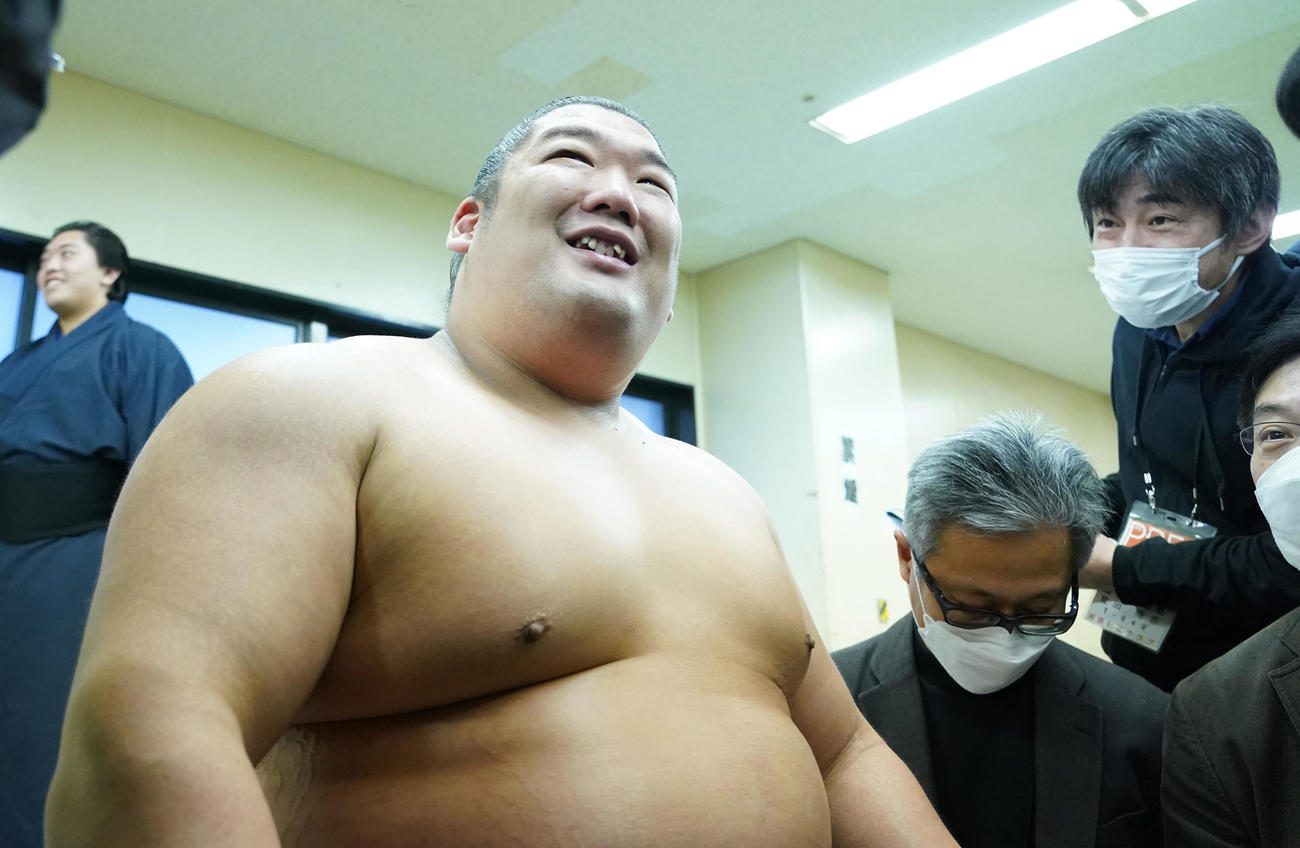 支度部屋で記者に囲まれ笑顔を見せる尊富士