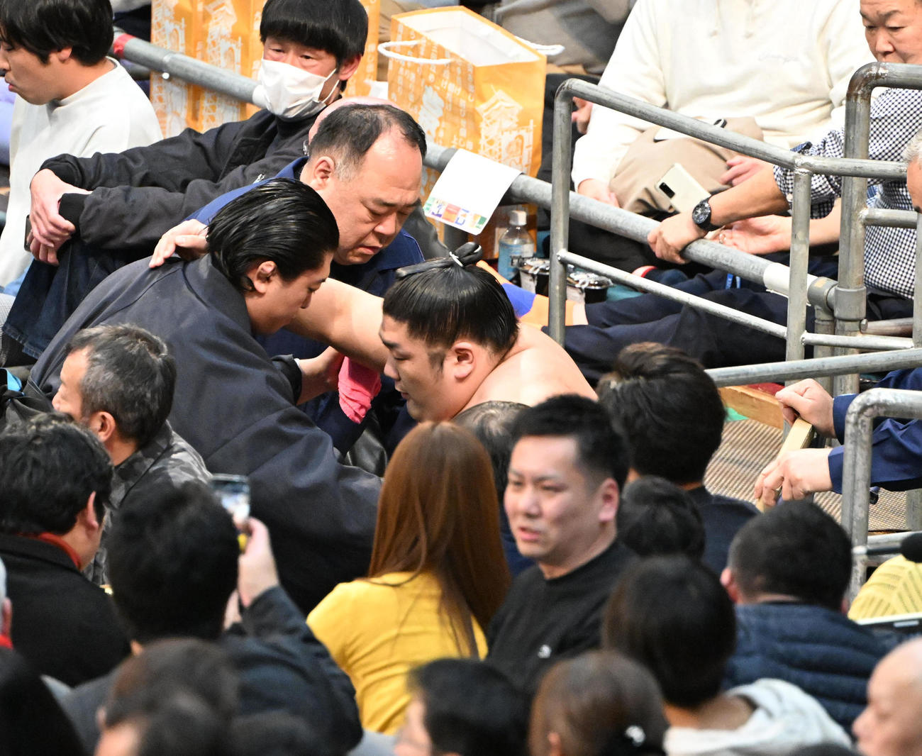 付き人の肩を借り車椅子に乗せられて引き揚げる尊富士（撮影・和賀正仁）