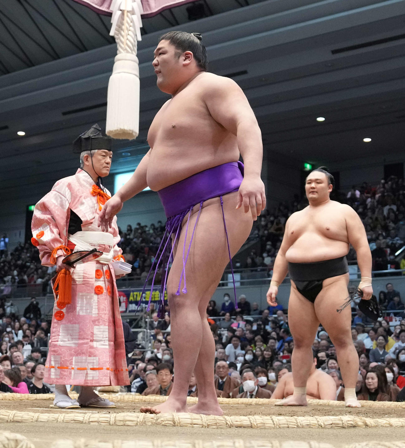 右足をかばいながら厳しい表情を浮かべる尊富士。右奥は朝乃山（撮影・小沢裕）