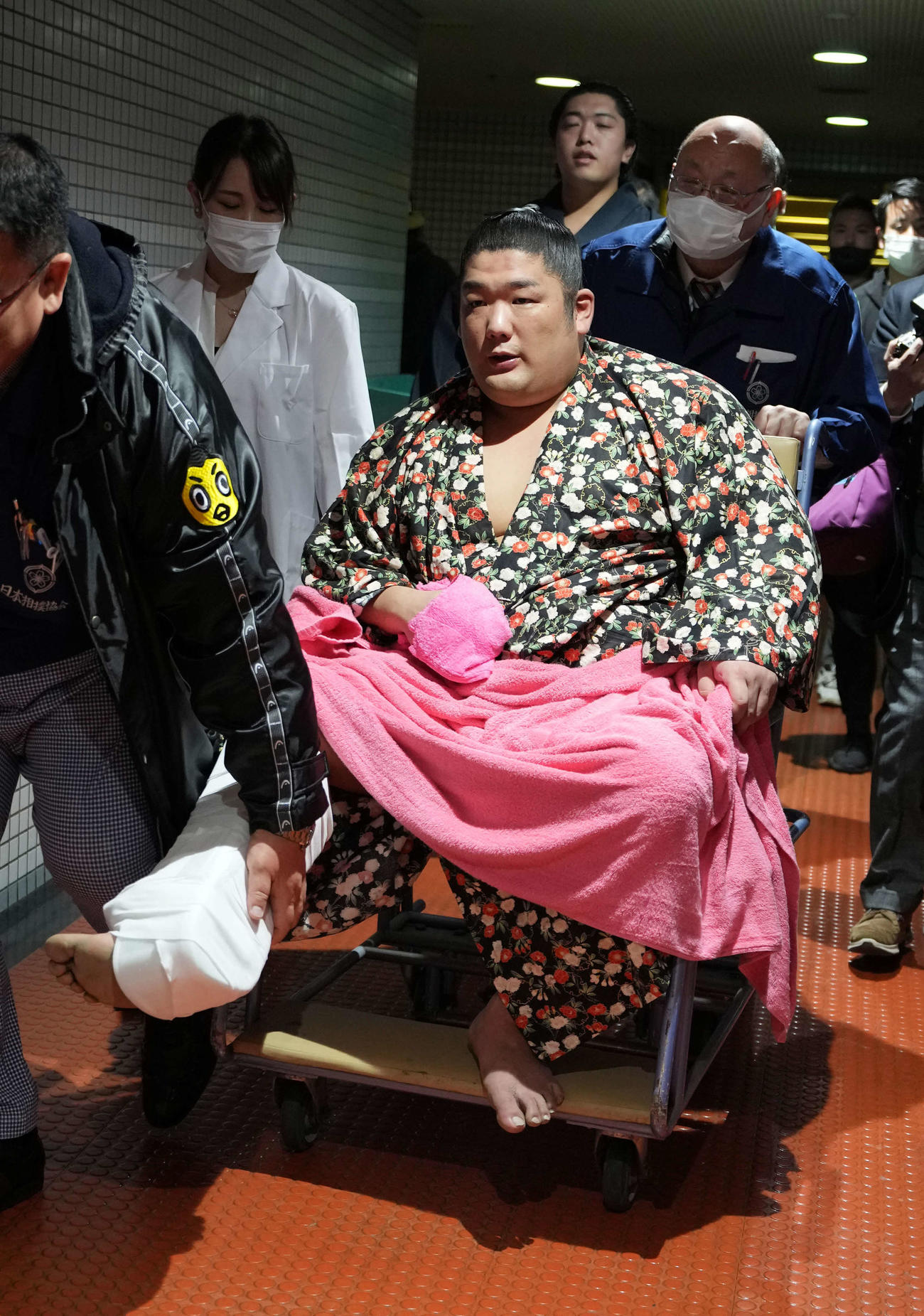 痛めた右足首を固定された状態で車いすに乗り移動する尊富士（撮影・小沢裕）
