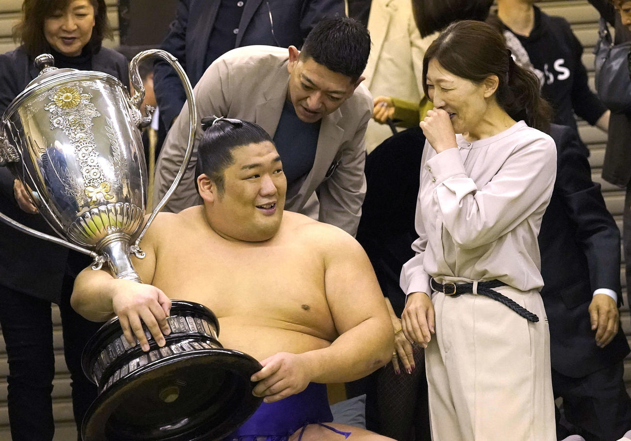 賜杯を手にし、母の石岡桃子さん（右）と笑顔で話す尊富士