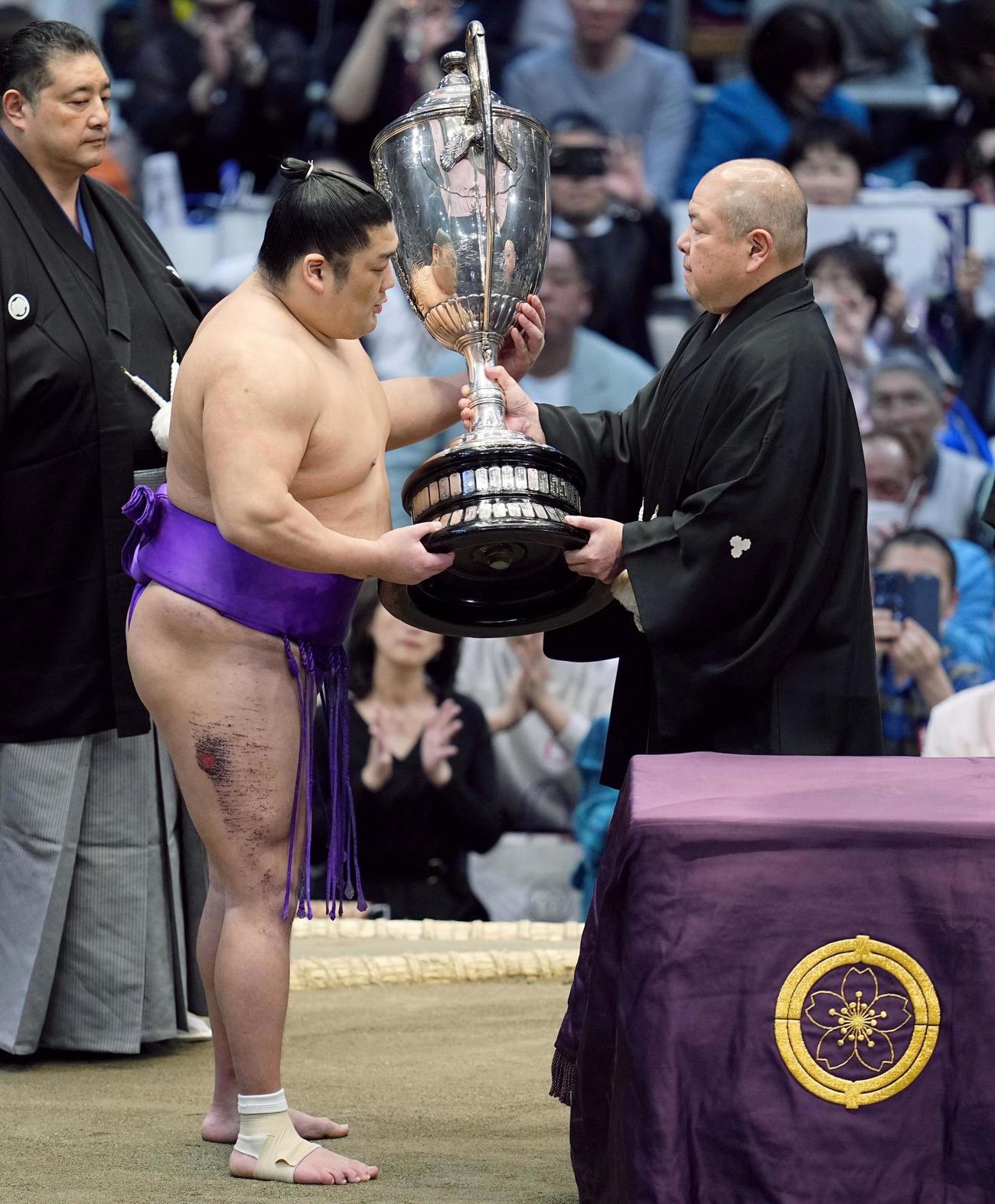 大相撲春場所で新入幕優勝を果たし、日本相撲協会の八角理事長（右）から賜杯を受け取る尊富士＝24日、エディオンアリーナ大阪（共同）