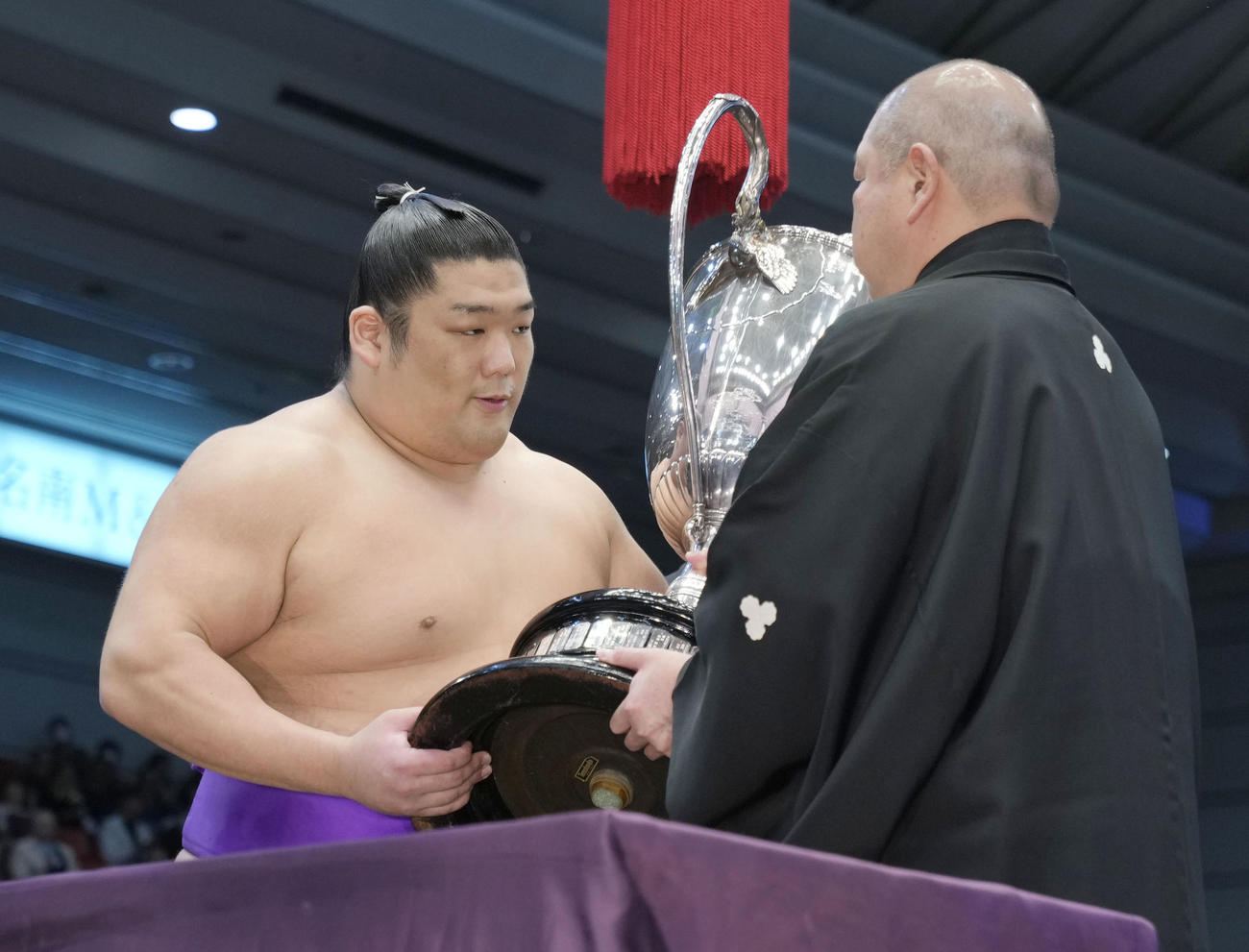 大相撲春場所で110年ぶりとなる新入幕優勝を果たし、日本相撲協会の八角理事長（右）から賜杯を受け取る尊富士＝24日、エディオンアリーナ大阪（共同）