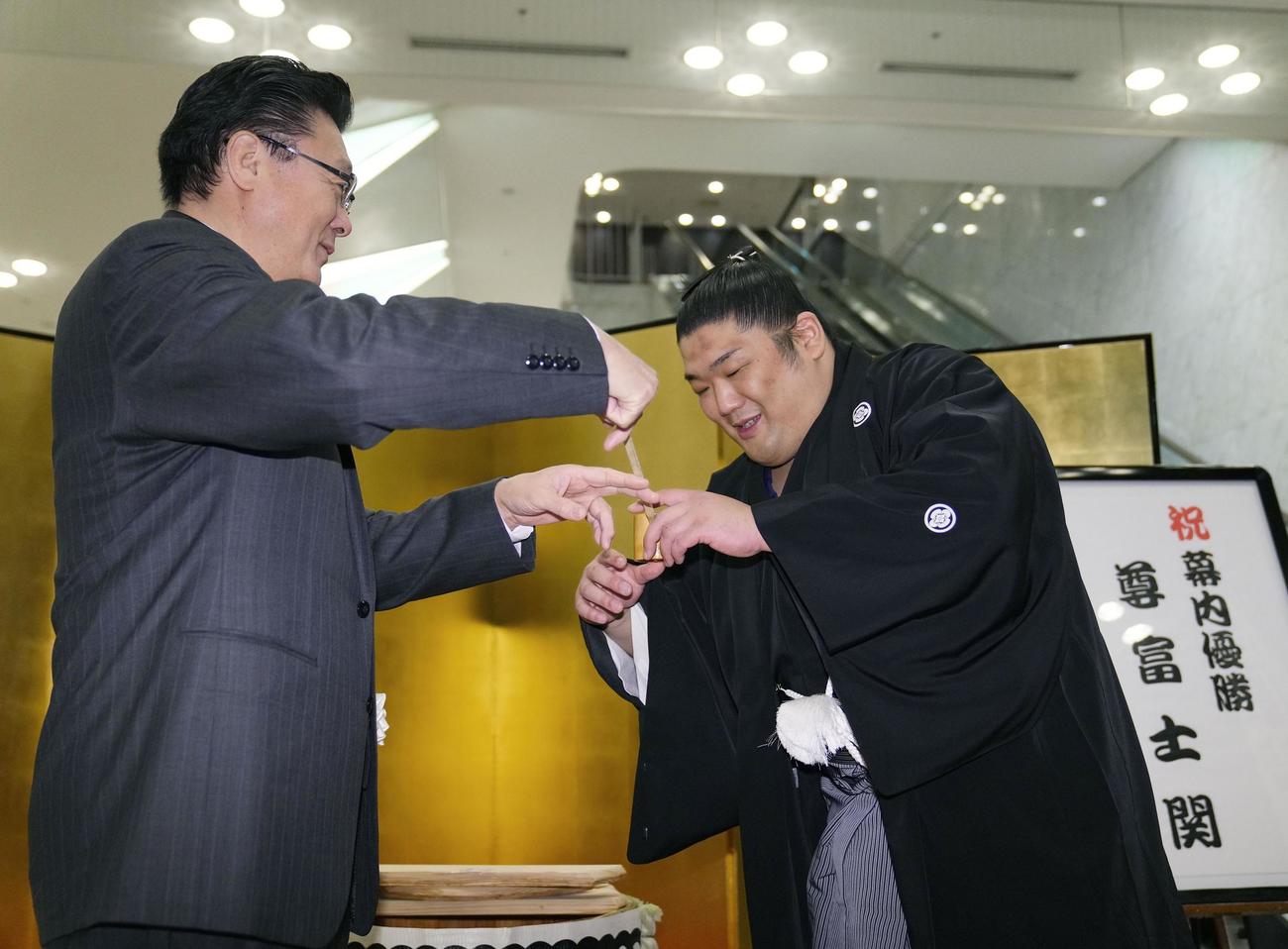 初優勝し、伊勢ケ浜親方（左）に水をつけてもらう尊富士（共同）