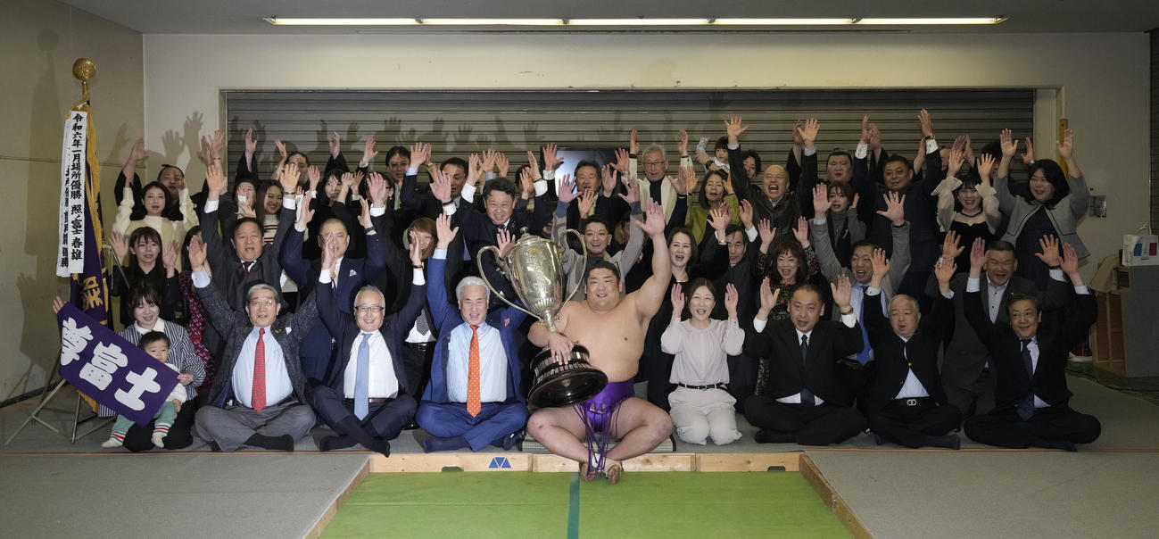 右足負傷を乗り越え優勝し、関係者とともにバンザイする尊富士