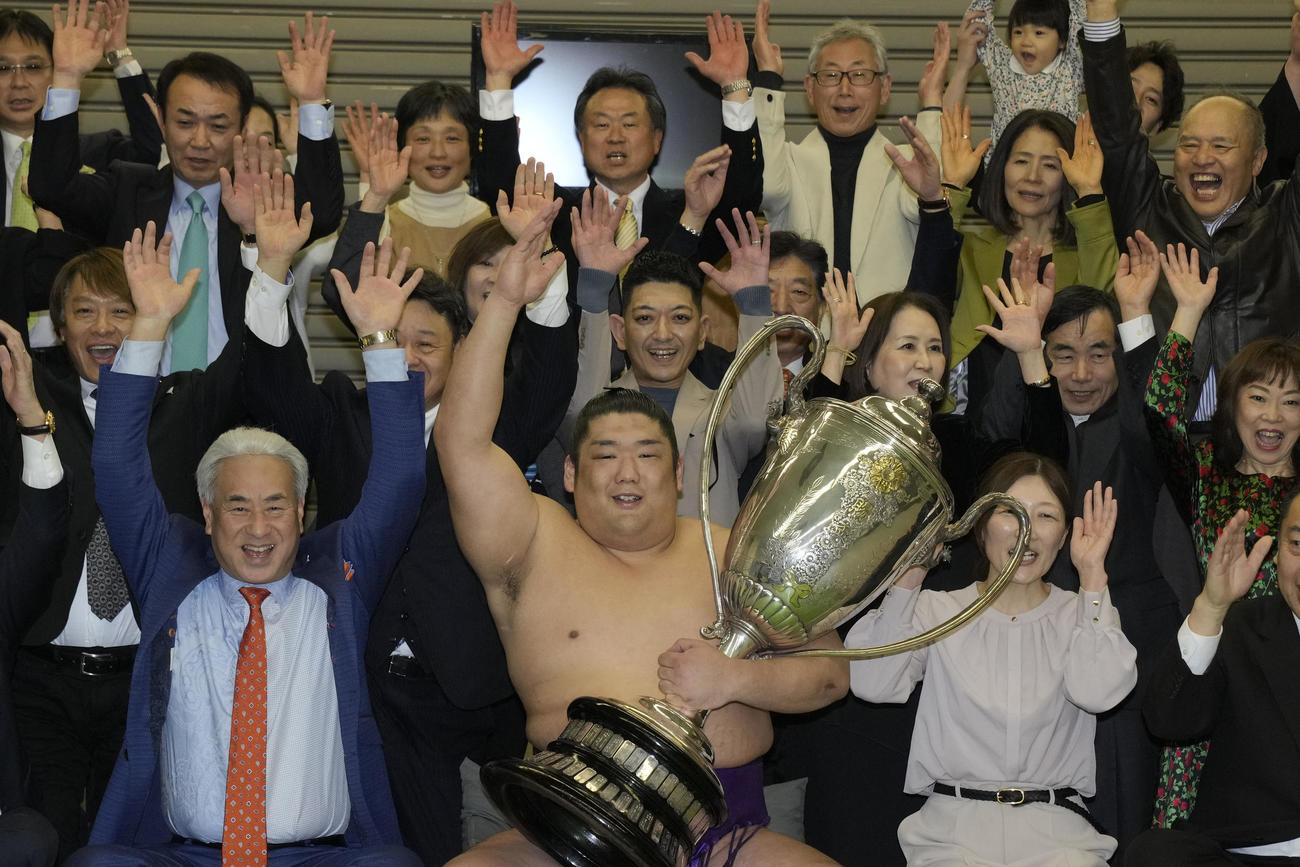 右足負傷を乗り越え優勝し、関係者とともにバンザイする尊富士