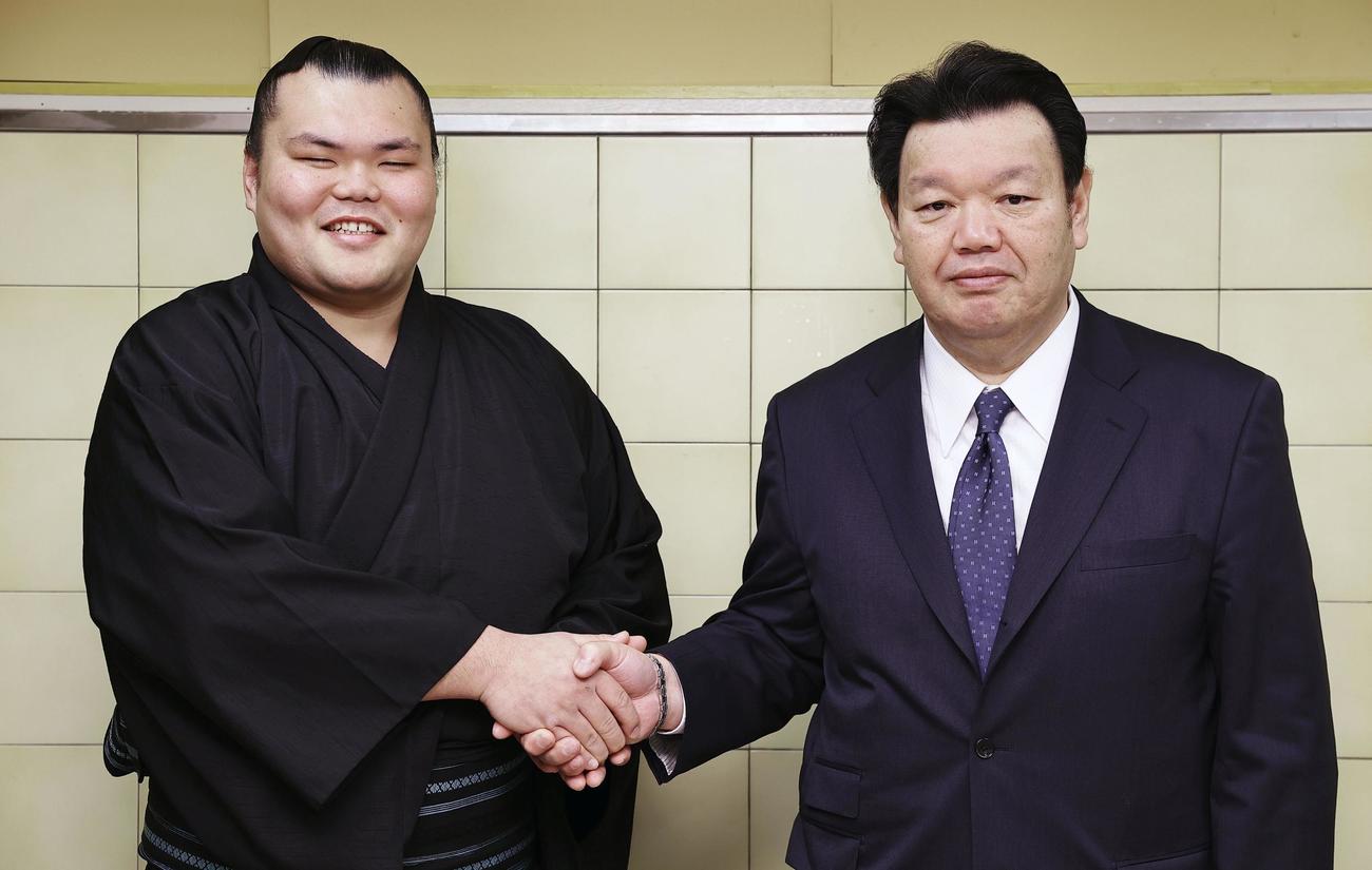 新十両昇進を決め、春日野親方（右）と握手する栃大海（共同）