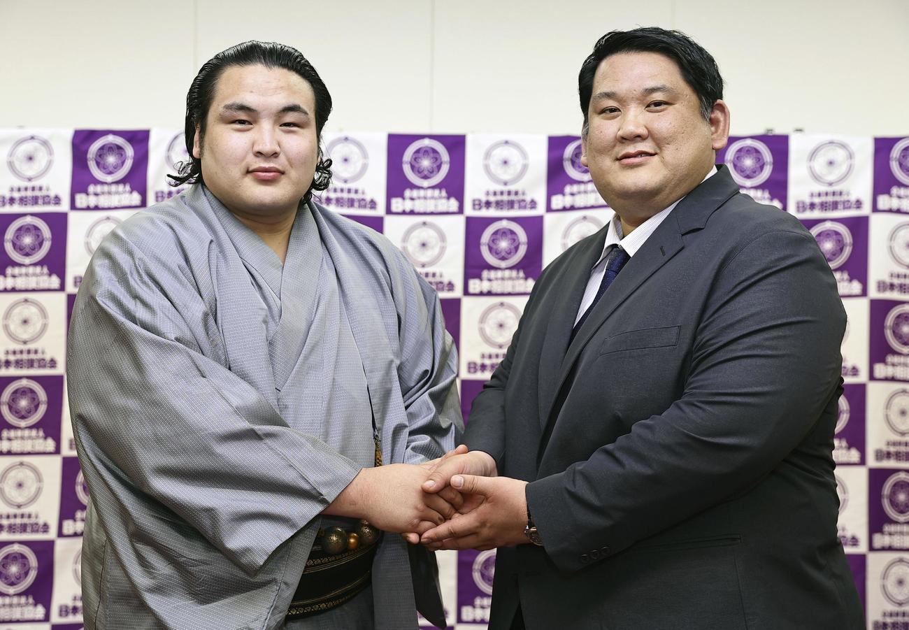 新十両昇進を決め、阿武松親方（右）と握手する阿武剋（共同）