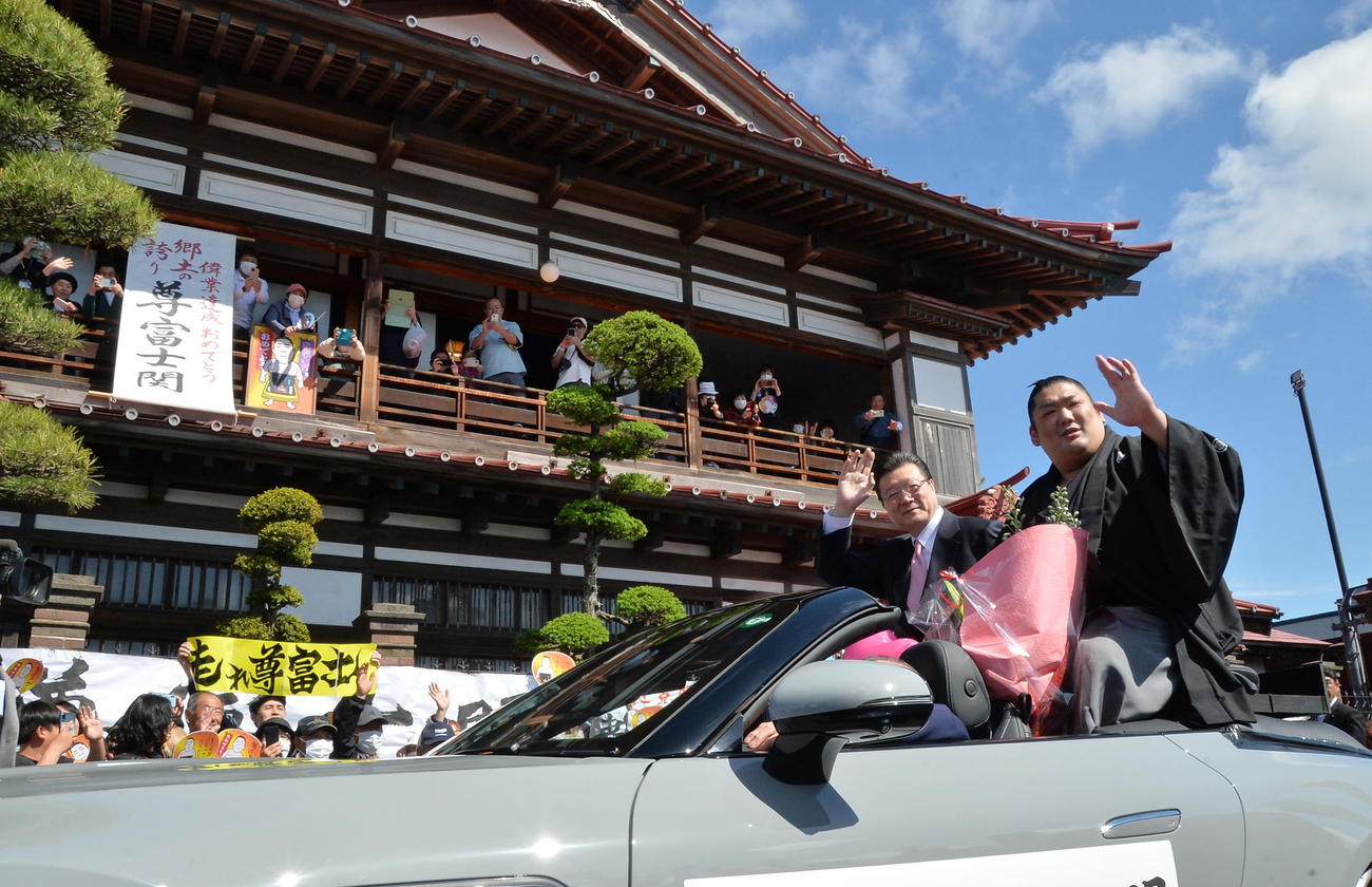 同郷の太宰治の記念館「斜陽館」の前を通過し、応援に手を振る尊富士（右）（撮影・濱本神威）