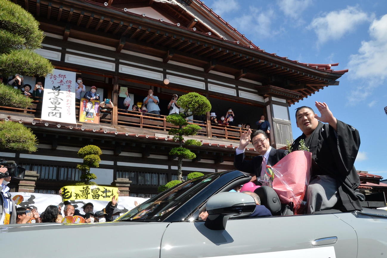 同郷の太宰治の記念館「斜陽館」の前を通過し、応援に手を振る尊富士（右）（撮影・濱本神威）