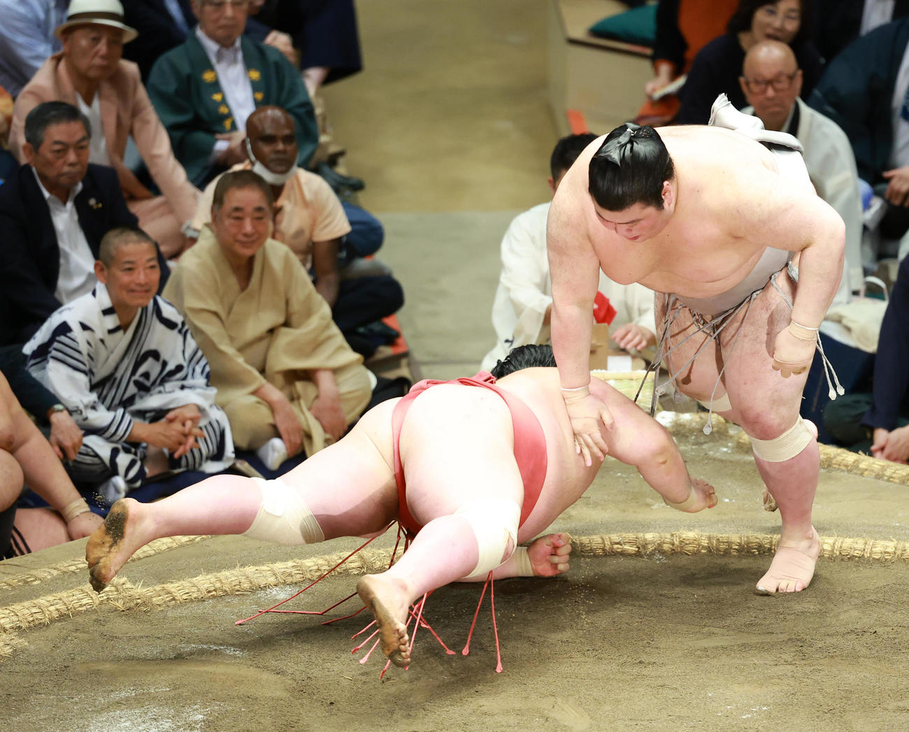 阿武咲（左）をはたき込みで破る熱海富士。観戦する三遊亭好楽の姿も（後列左から２人目）（撮影・中島郁夫）