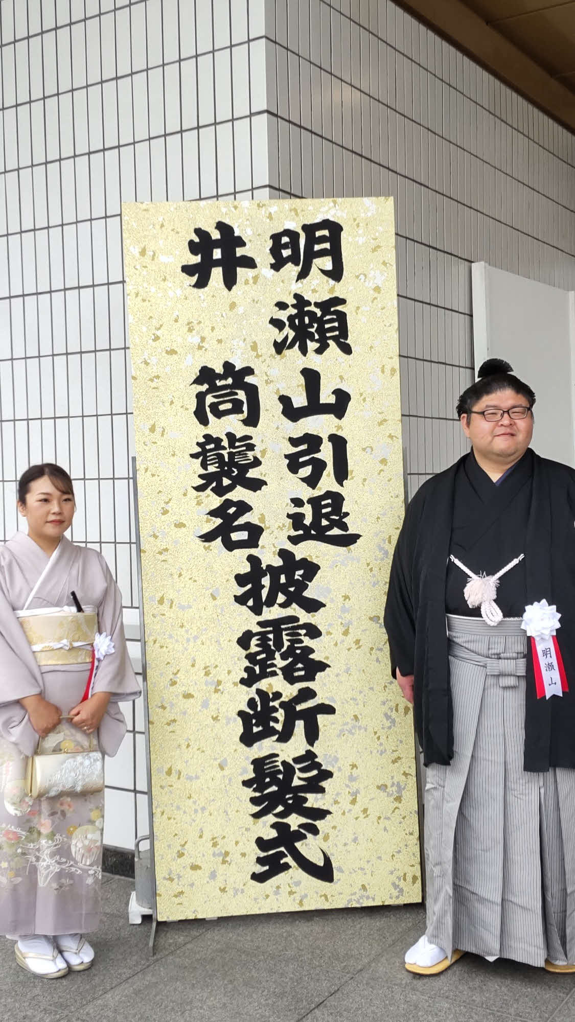 会場入り口で招待者を迎え入れる井筒親方（右）と晴香夫人