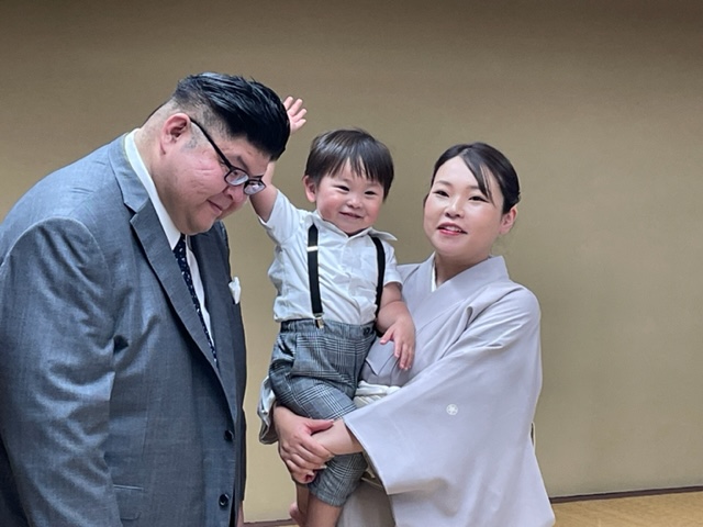 断髪式を終え整髪後、長男颯之佑君に頭を触られる井筒親方（左）。右は晴香夫人