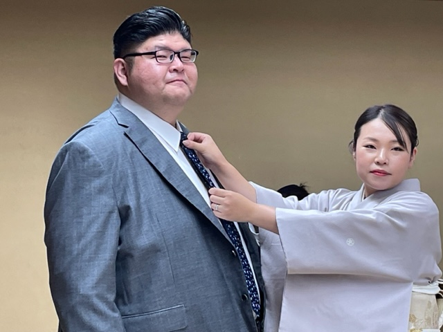 断髪式を終え整髪後、晴香夫人（右）からネクタイを締められる井筒親方