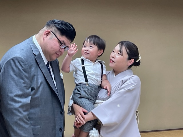 断髪式を終え整髪後、長男颯之佑君に頭を触られる井筒親方（左）。右は晴香夫人