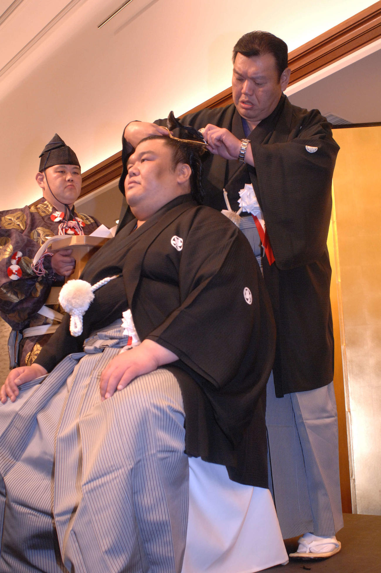 2014年4月、師匠の春日野親方（右）の止めバサミで、まげに別れを告げる元幕内木村山の岩友親方（後方左は行司の木村秋治郎）