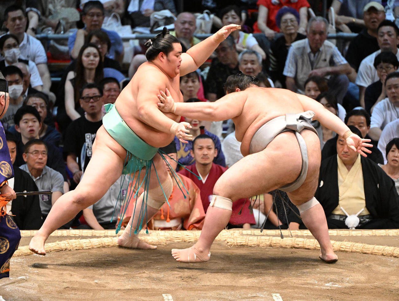 大相撲名古屋場所2日目、琴桜（左）は寄り切りで熱海富士を破る。奥に見えるのは名古屋おもてなし武将隊の織田信長（24年7月15日撮影）