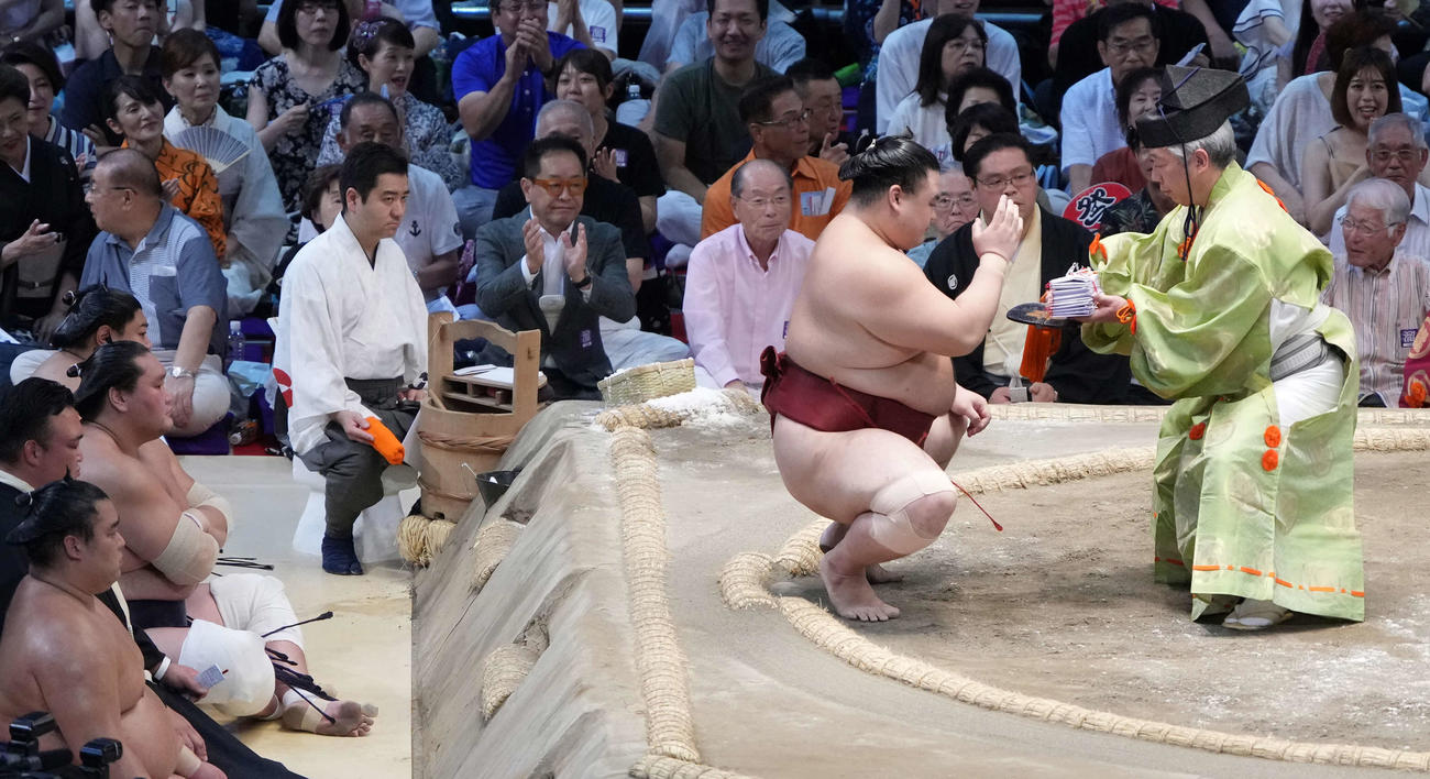 懸賞金を受け取る隆の勝。左橋は土俵下控えの照ノ富士（撮影・小沢裕）