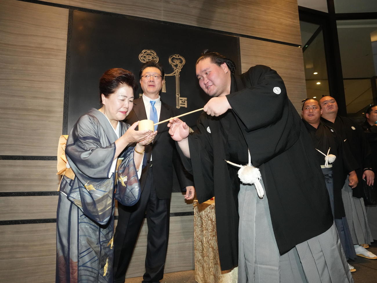 千秋楽パーティー会場で優勝の出迎えを受けた照ノ富士は、左からおかみの淳子さん、伊勢ケ浜親方に水を付ける＝2024年7月28日