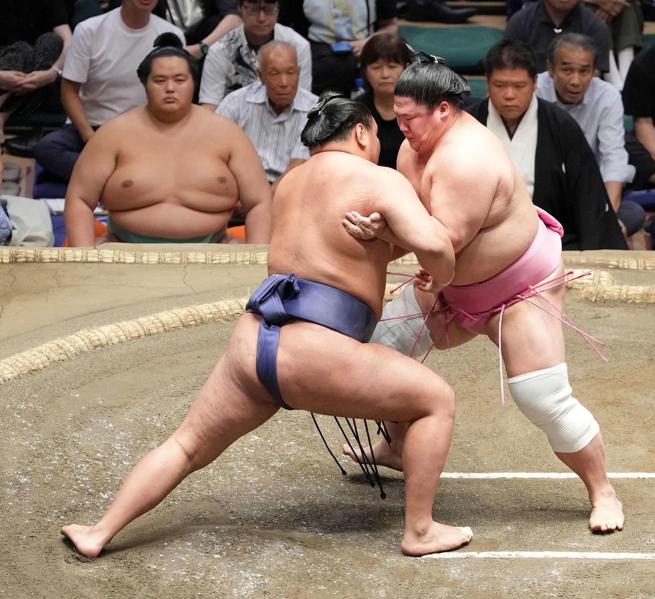 豊昇龍の攻めをこらえる宇良（右）。左奥は土俵下控えの琴桜（撮影・小沢裕）
