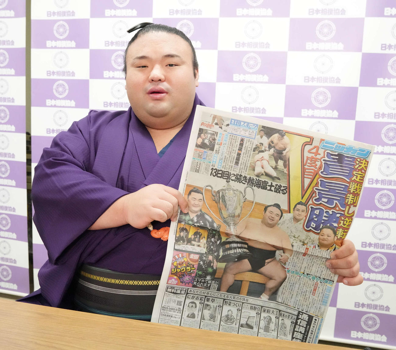 2023年9月、優勝一夜明け会見に臨んだ貴景勝は1面に掲載された本紙を手に笑顔を見せる