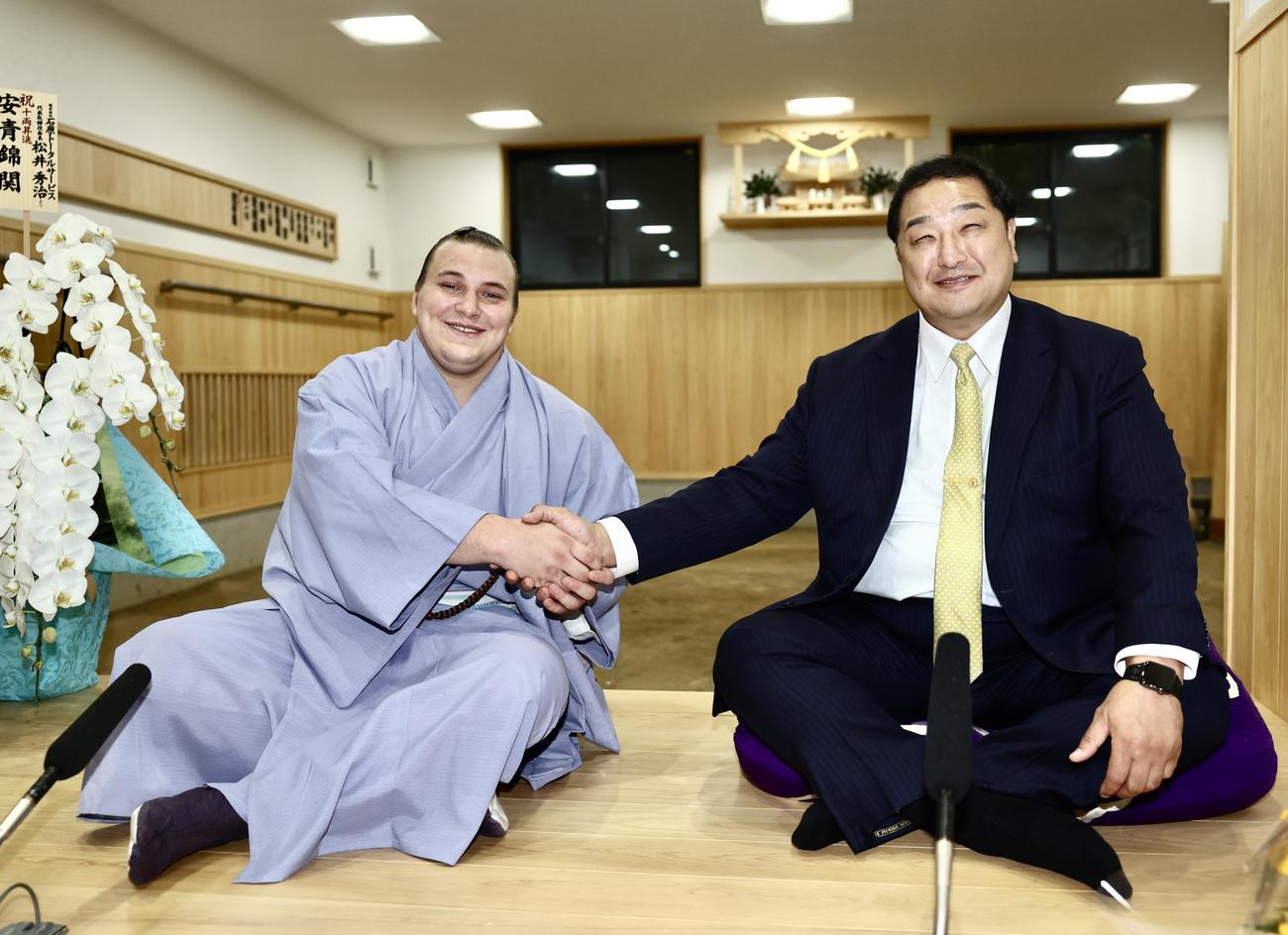 新十両に昇進した安青錦（左）は、安治川親方と笑顔で握手を交わす（撮影・河田真司）