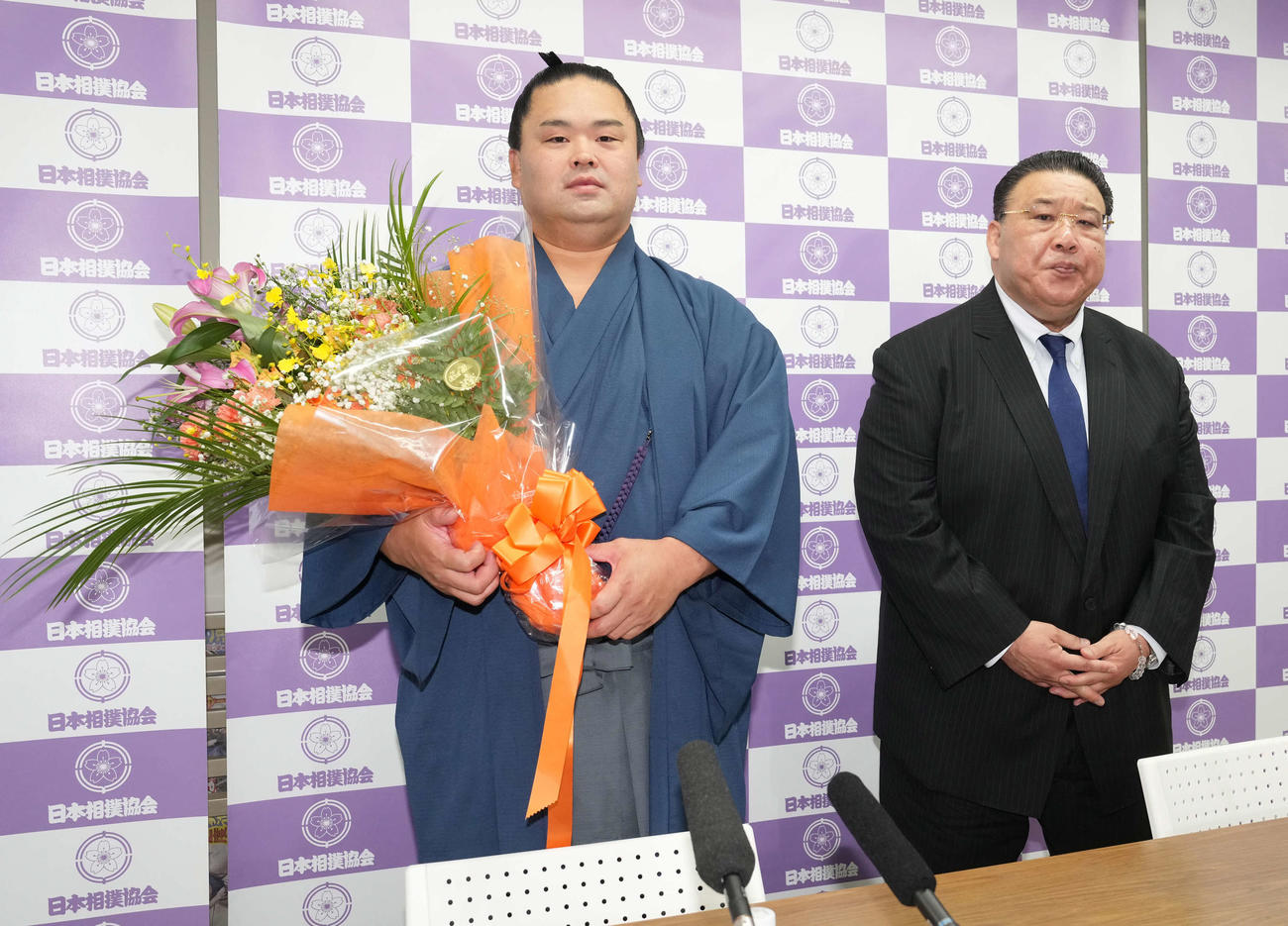 引退会見に臨み花束贈呈を受ける妙義龍。右は師匠の境川親方（撮影・小沢裕）