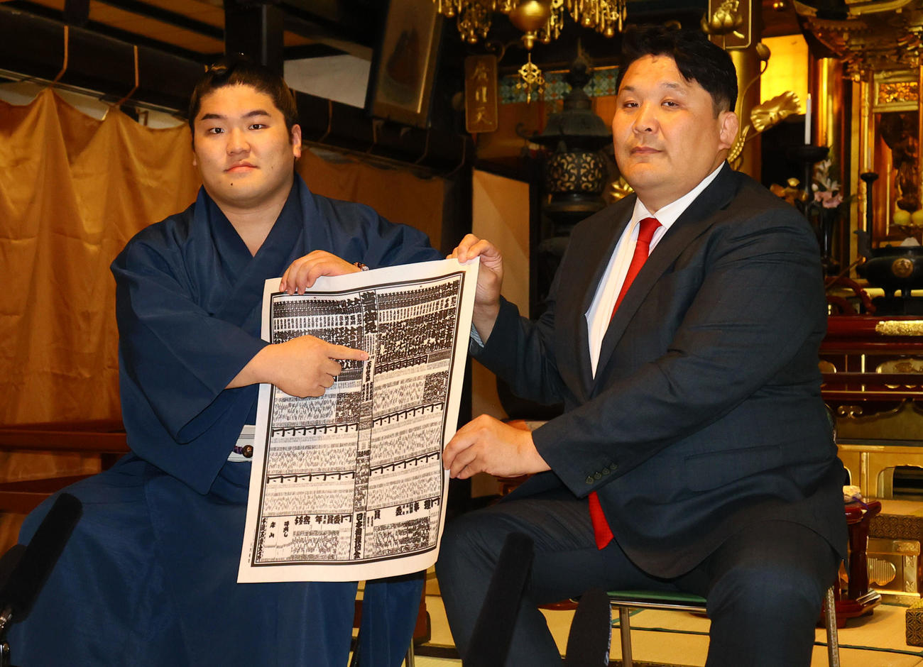 新番付表を手にしこ名前を指さす朝紅龍。右は高砂親方（撮影・鬼束羽瑠菜）