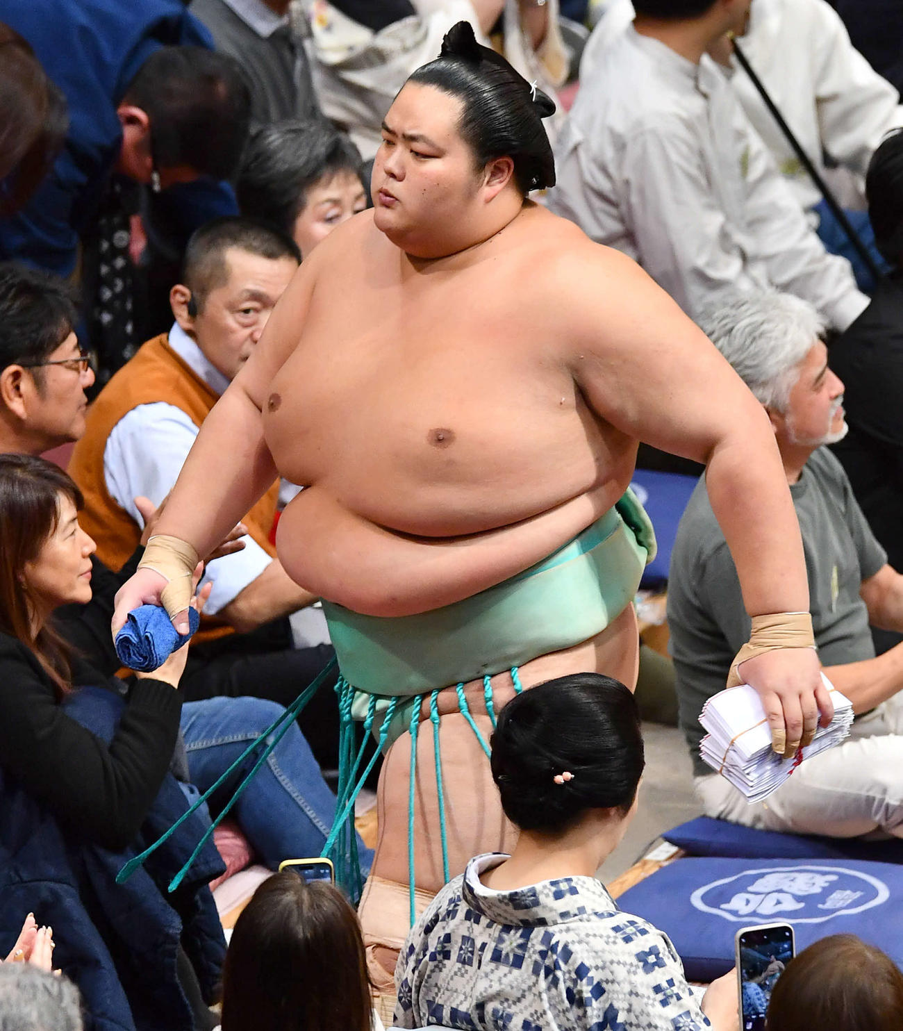 大相撲九州場所13日目　上手投げで隆の勝を破り、懸賞の束を手に花道を引き揚げる琴桜（撮影・岩下翔太）