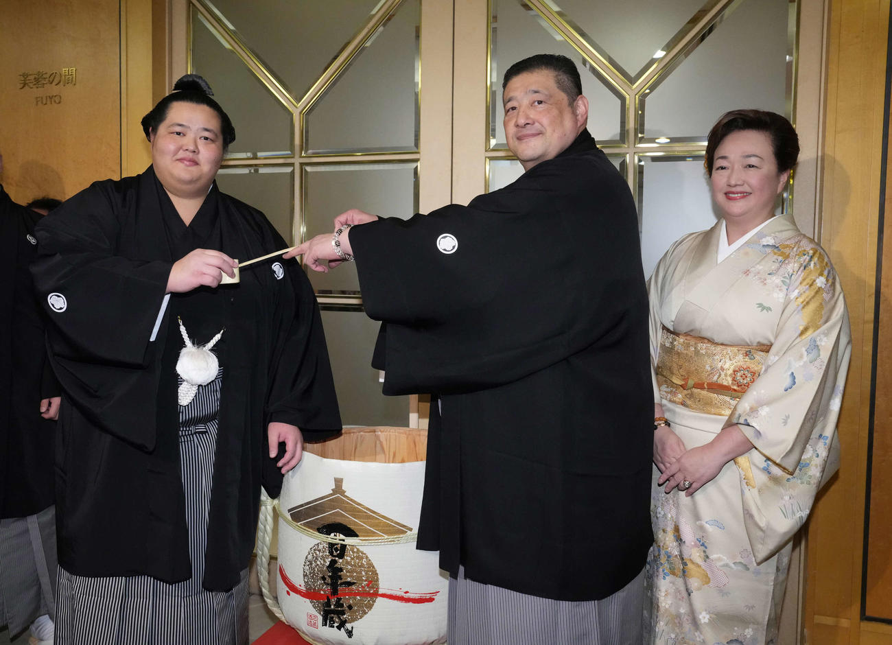 初優勝を飾った琴桜（左）は千秋楽パーティー会場で父である師匠の佐渡ケ嶽親方から水を付けてもらう。右は母でおかみの真千子さん（撮影・小沢裕）