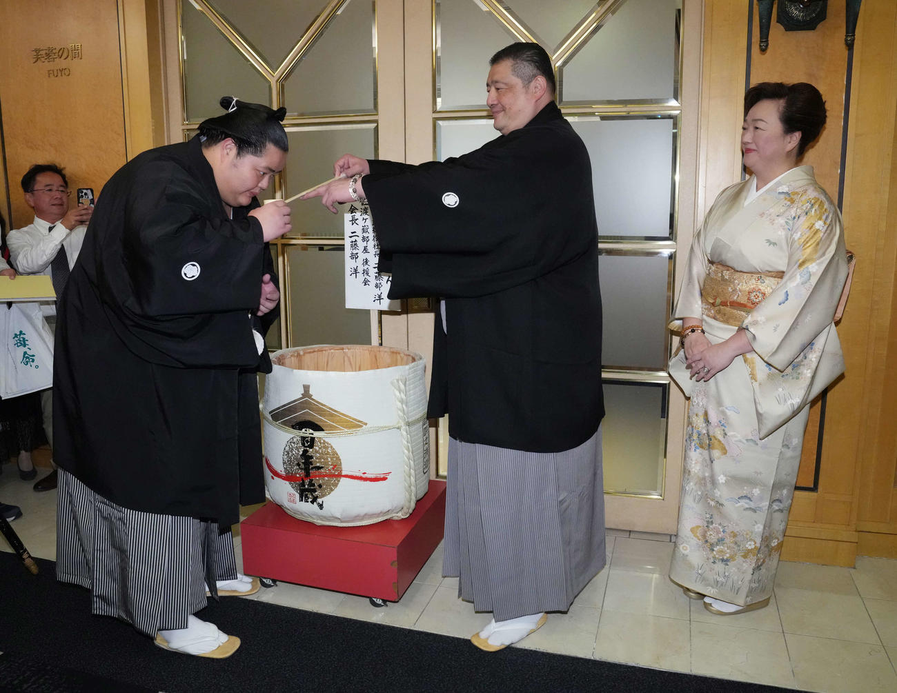初優勝を飾った琴桜（左）は千秋楽パーティー会場で父である師匠の佐渡ケ嶽親方から水を付けてもらう。右は母でおかみの真千子さん（撮影・小沢裕）