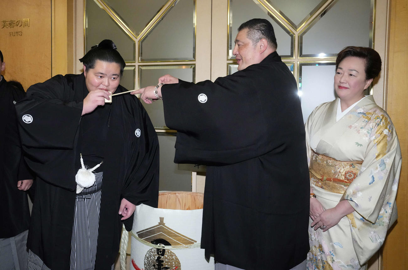 初優勝を飾った琴桜（左）は千秋楽パーティー会場で父である師匠の佐渡ケ嶽親方から水を付けてもらう。右は母でおかみの真千子さん（撮影・小沢裕）