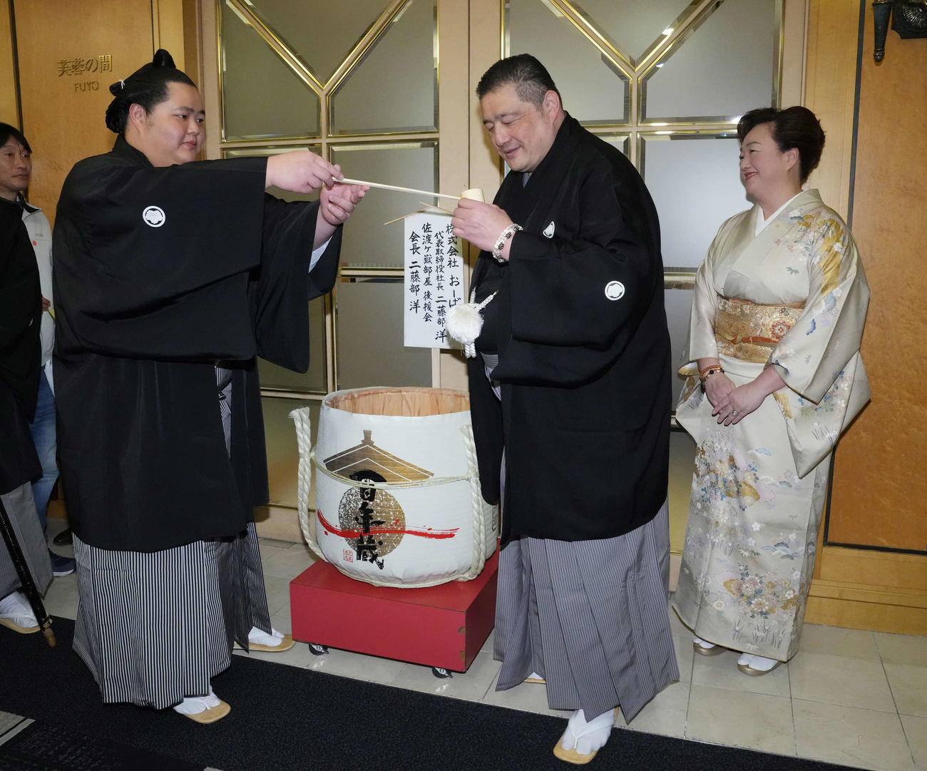 初優勝を飾った琴桜（左）は千秋楽パーティー会場で父である師匠の佐渡ケ嶽親方に水を付ける。右は母でおかみの真千子さん（撮影・小沢裕）