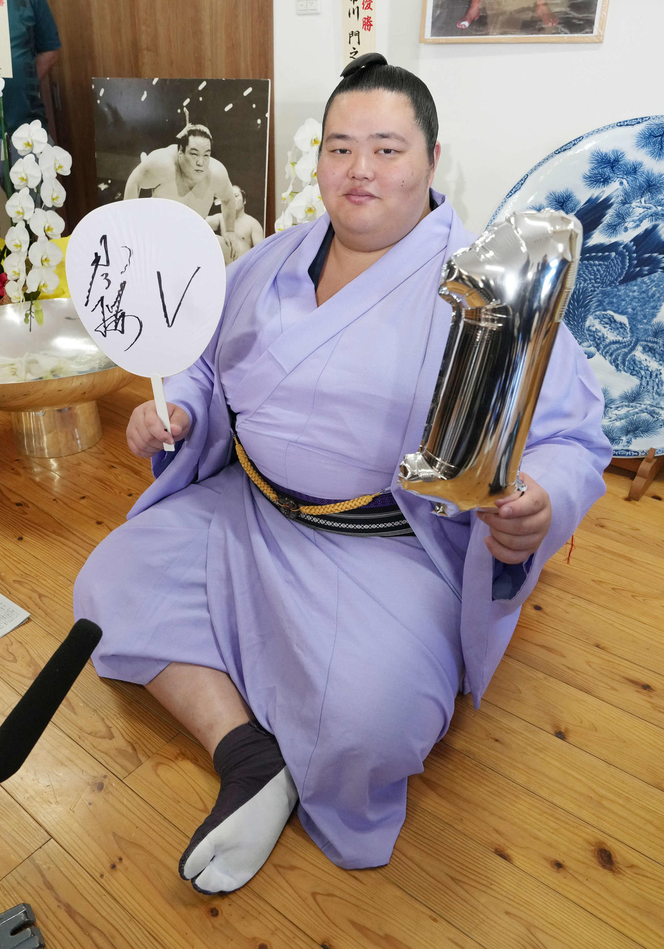 琴桜は初優勝の一夜明け会見で先代琴桜の写真パネルを背にカメラマンの要望に応えて「1」のバルーンを手に笑顔で記念撮影に臨む（撮影・小沢裕）