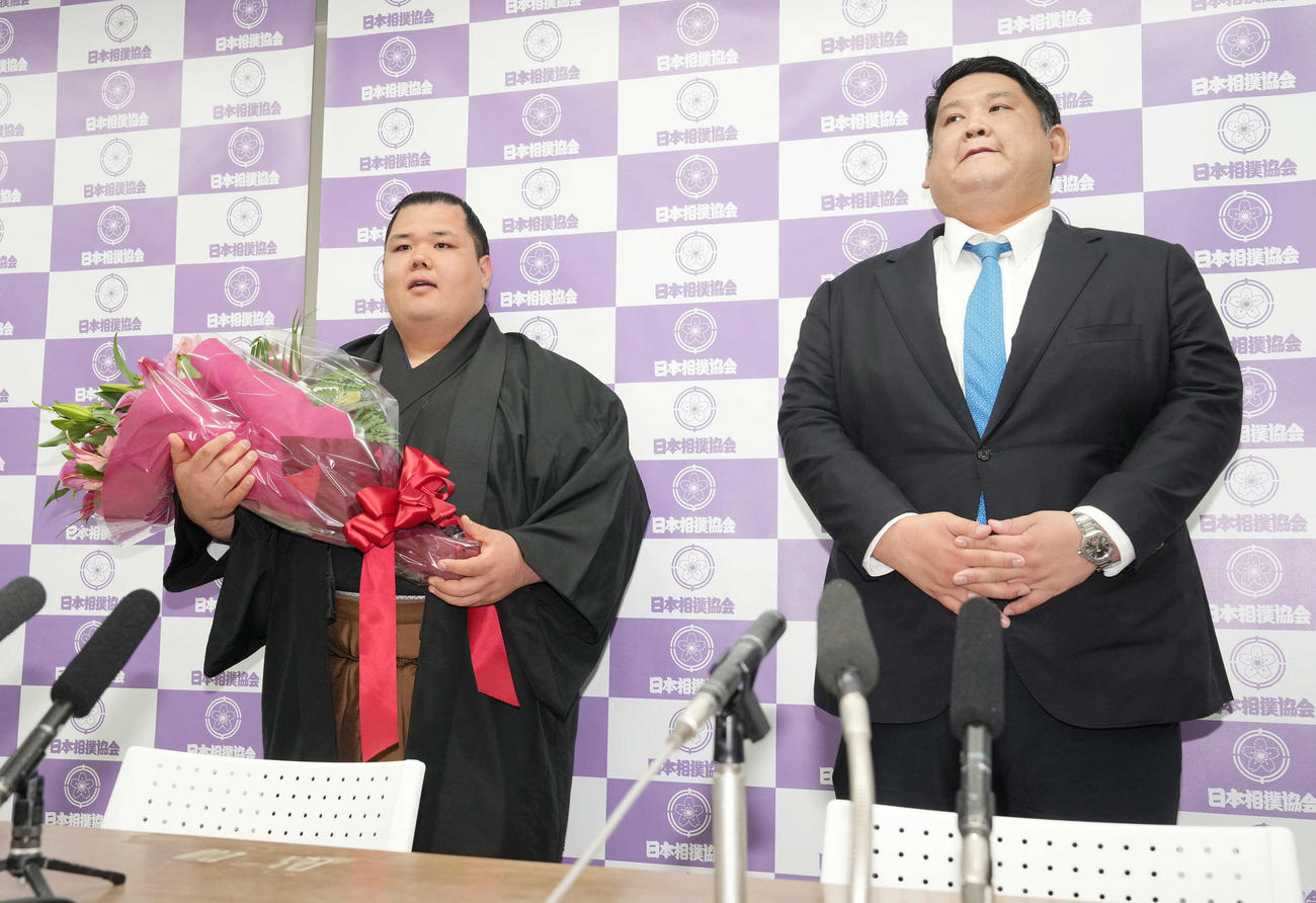 引退会見を終え花束を手に笑顔を見せる阿武咲。右は師匠の阿武松親方（撮影・小沢裕）