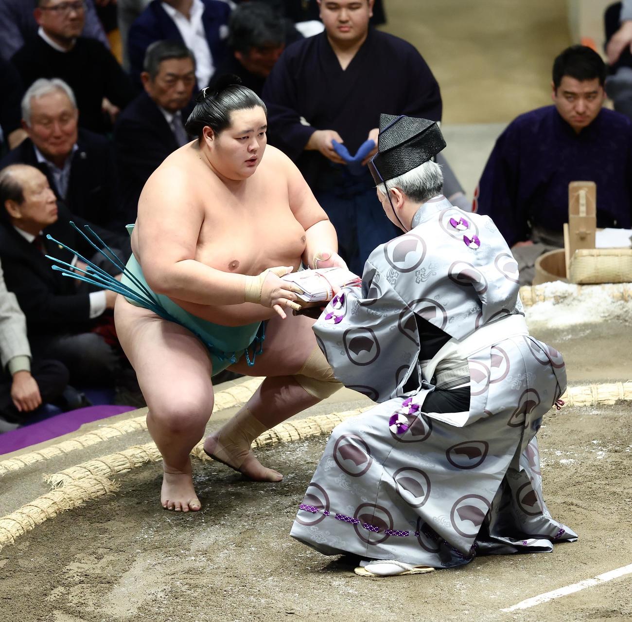 隆の勝を寄り切りで破り、懸賞金の束を受け取る琴桜（撮影・河田真司）