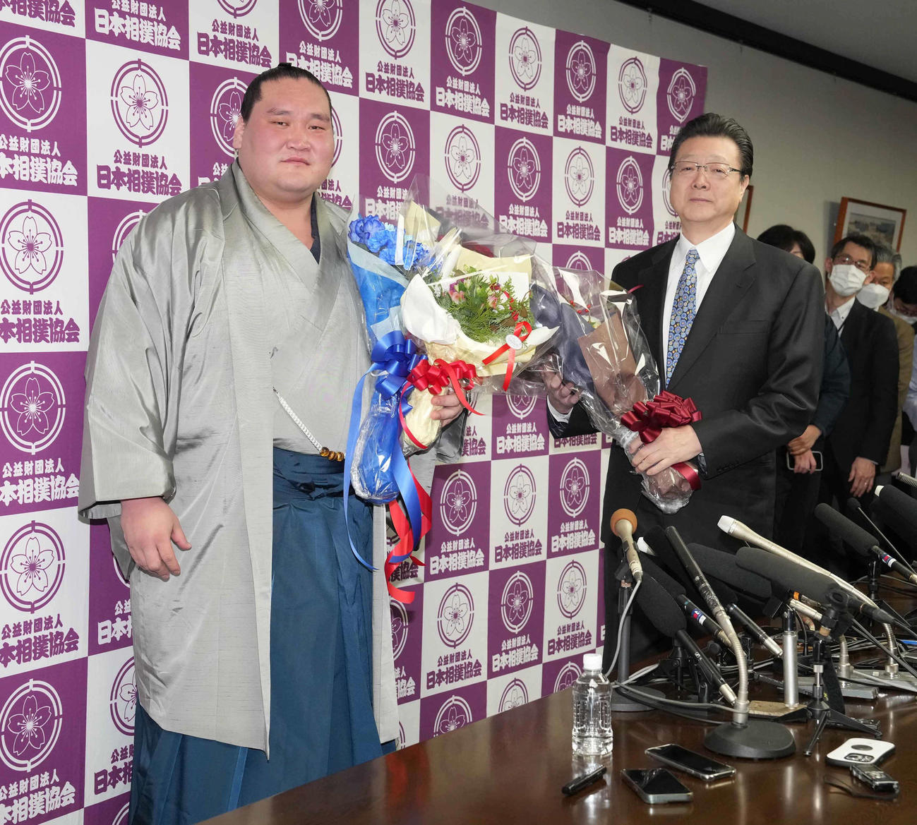 引退会見を終えた元横綱照ノ富士は花束を手に記念撮影に臨む。右は師匠の伊勢ケ浜親方（撮影・小沢裕）
