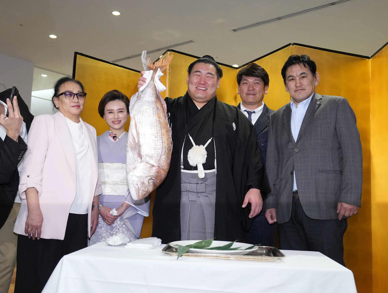 優勝した豊昇龍（中央）は千秋楽パーティーで、左から母ナルマンダフさん、おかみの舞美さん、1人おいて立浪親方、父スガラクチャさんの祝福を受けながらお祝いの鯛を持ち上げる（撮影・小沢裕）
