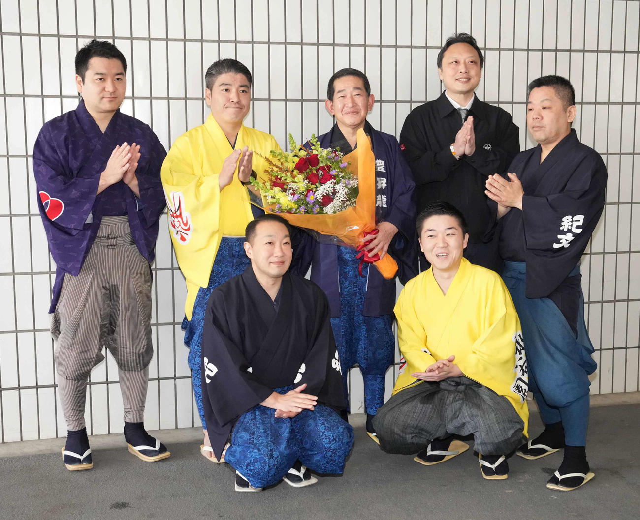 定年退職する呼び出しの次郎（後列中央）は一門の呼び出したちから花束贈呈を受け記念撮影に臨む（撮影・小沢裕）