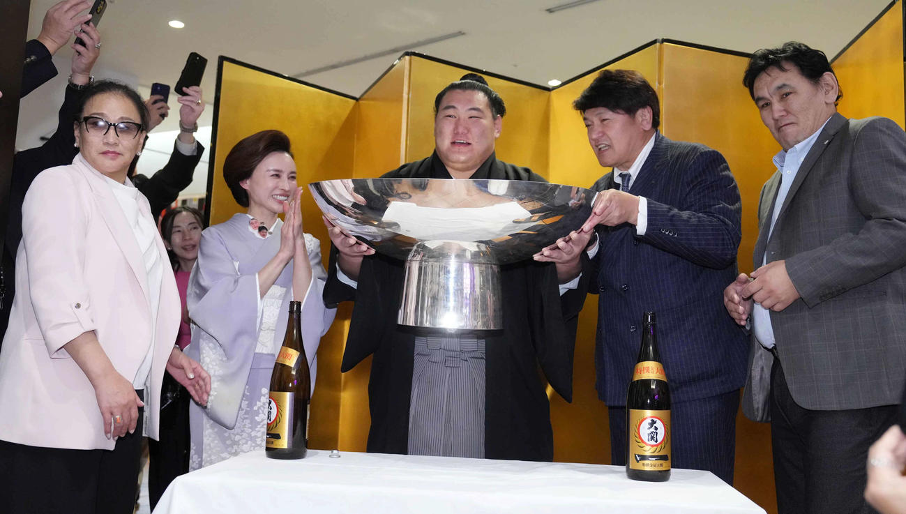 優勝した豊昇龍（中央）は千秋楽パーティーで、左から母ナルマンダフさん、おかみの舞美さん、1人おいて立浪親方、父スガラクチャさんから銀杯にそそがれたお祝いのお酒を飲み笑顔を見せる（撮影・小沢裕）