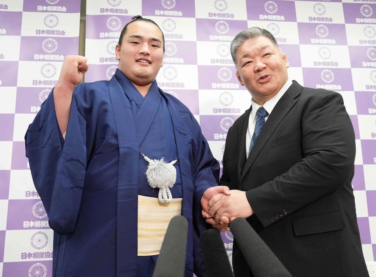 春場所での新十両昇進が決まりポーズを決める大辻。右は師匠の高田川親方（撮影・小沢裕）
