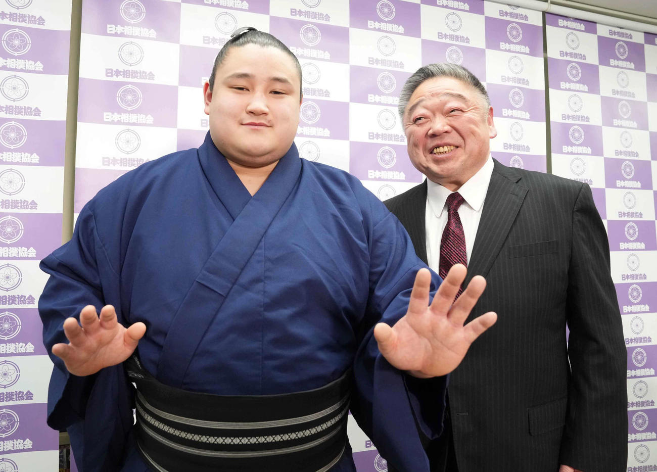 春場所の新十両昇進会見に臨み得意の突き押しでポーズを決める若ノ勝。右は常盤山親方（撮影・小沢裕）