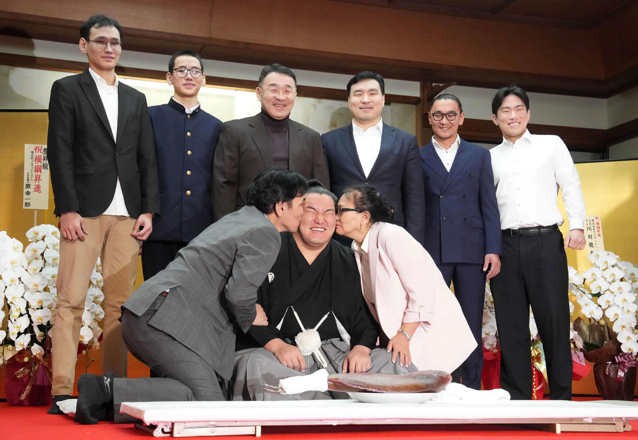 横綱昇進伝達式を終えた豊昇龍（中央）は父スガラグチャーさん（左）母ナルマンダフさん（右）から祝福のキスを受けながら家族と記念撮影に臨む（撮影・小沢裕）