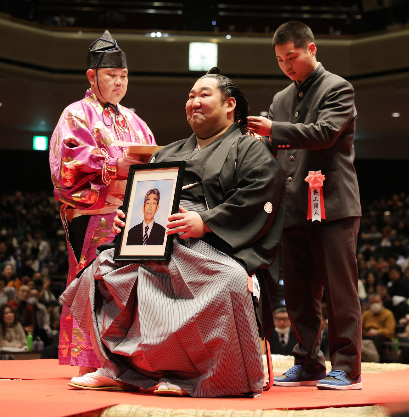 断髪式で、父順次さんの遺影を手に、おいの井上陽人さん（右）からはさみを入れられる徳勝龍（撮影・野上伸悟）