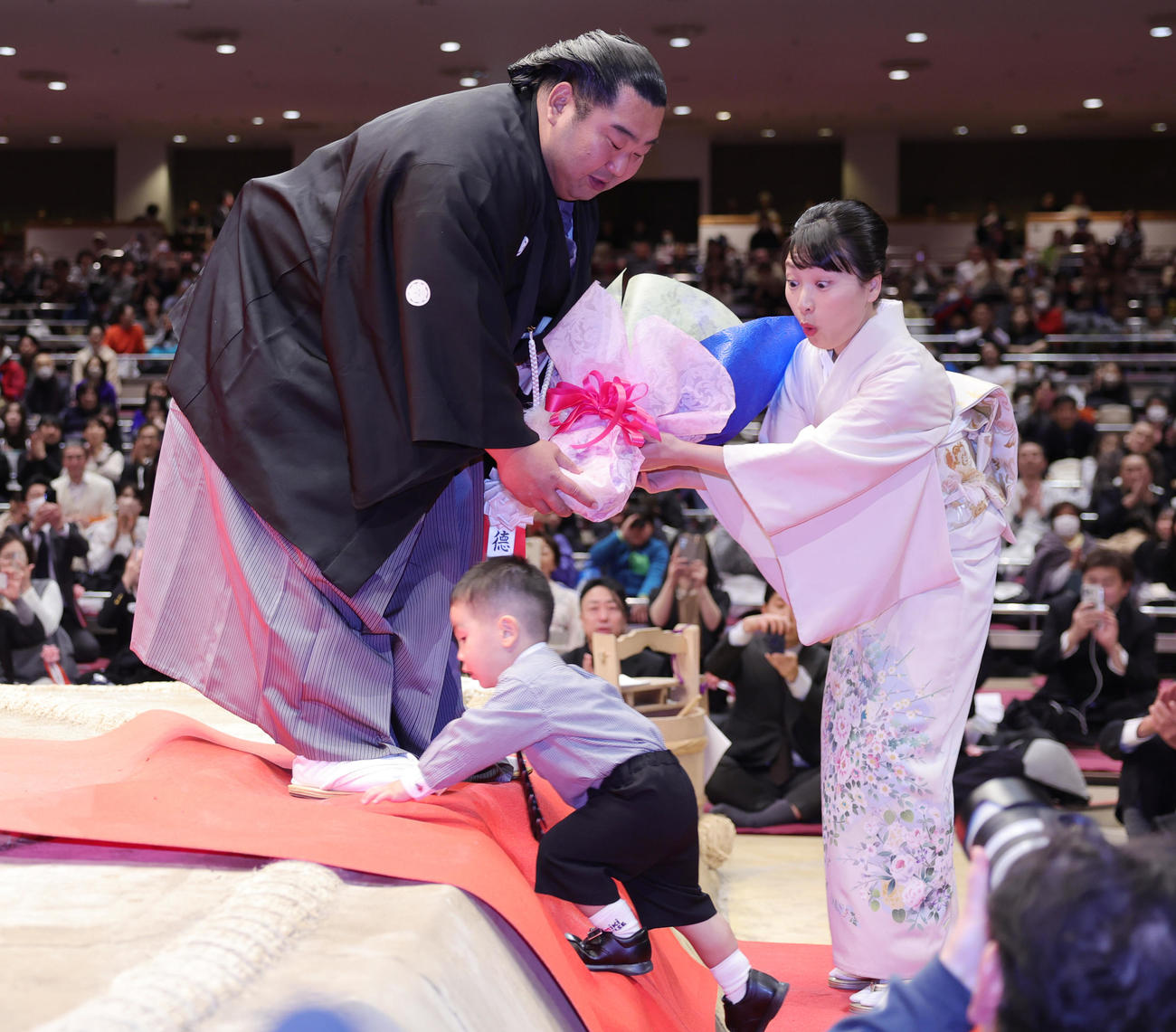 断髪式を終え、千恵夫人（右）から花束をもらった徳勝龍は、長男の風磨くんが土俵に上がろうとして慌てる（撮影・野上伸悟）