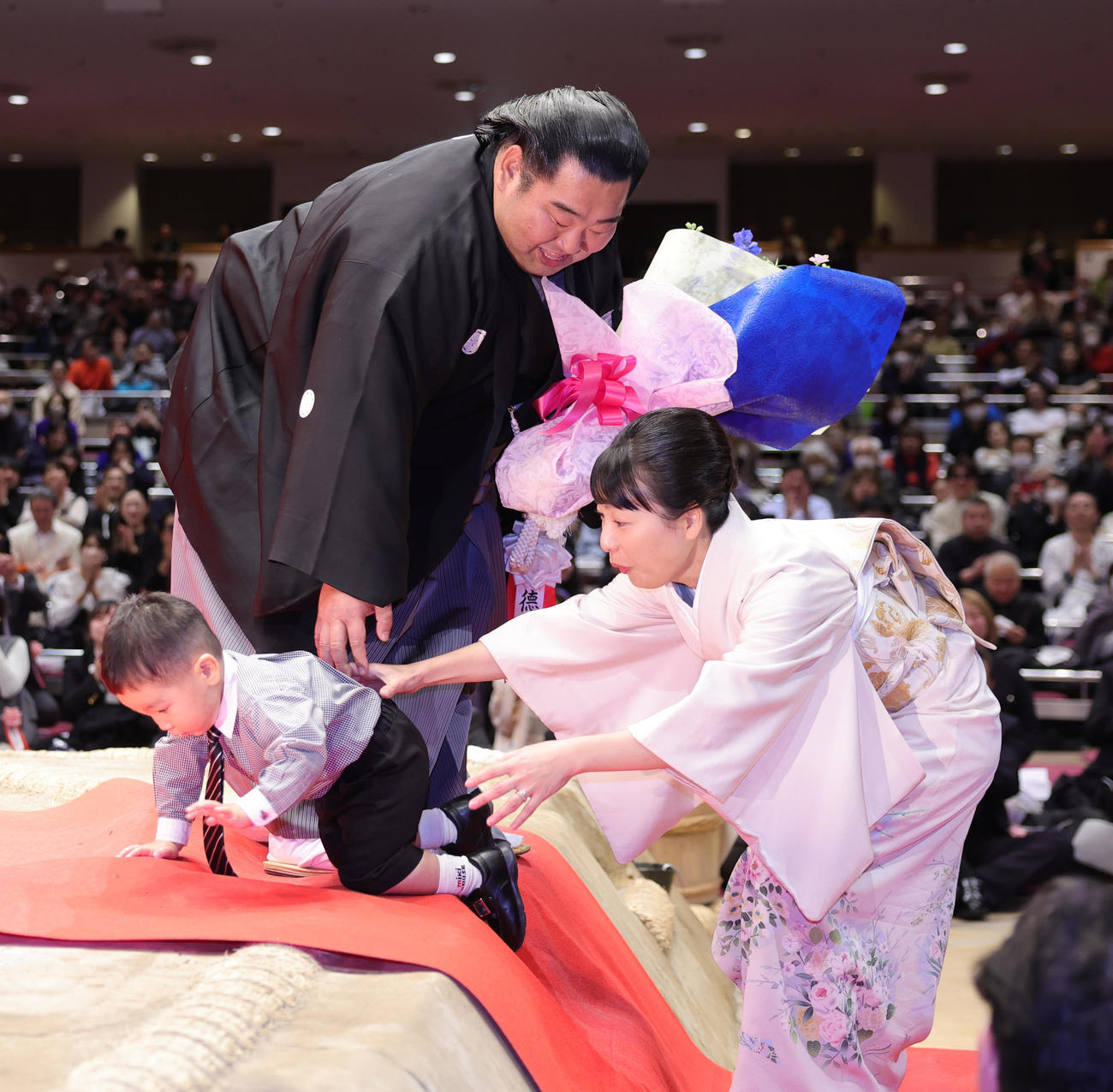断髪式を終え、千恵夫人（右）から花束をもらった徳勝龍は、長男の風磨くんが土俵に上がろうとして慌てる（撮影・野上伸悟）