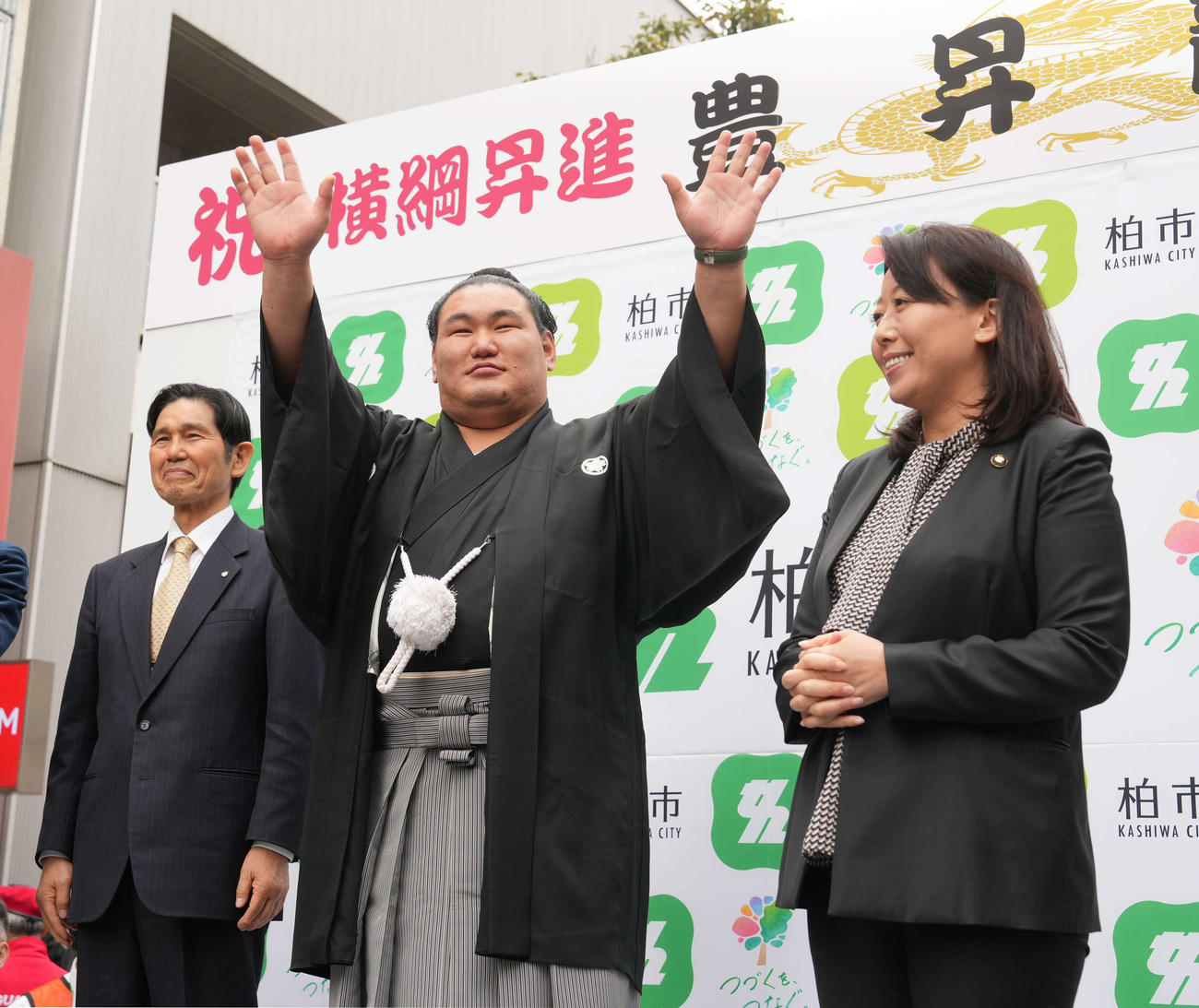 高校時代にゆかりのある千葉県柏市内で開催された横綱昇進祝賀パレードを終え壇上で詰め掛けた市民の声援に応える豊昇龍。左は日体柏高の氷海校長、右は柏市の太田市長（撮影・小沢裕）