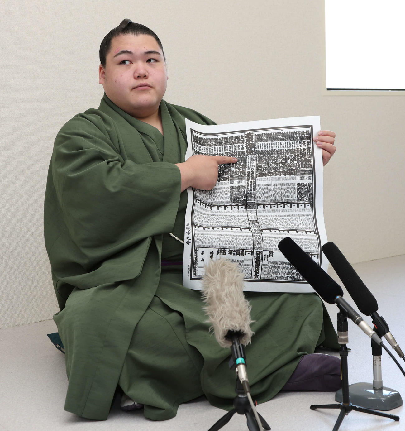 春場所で新関脇に昇進した王鵬はしこ名が載った番付を指さす（撮影・西尾就之）